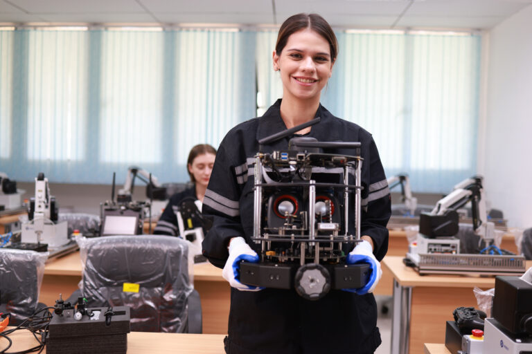 The  young  female electrician engineer  holding  the motherboard  prototype with a torch in her hand and looking at the camera in automated class